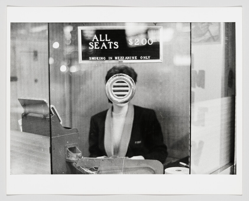 Ticket seller sits behind a glass booth beneath a sign reading "All seats $2.00."