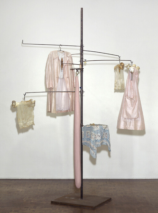 A metal stand displays several vintage pink dresses and delicate garments hanging like a mobile.
