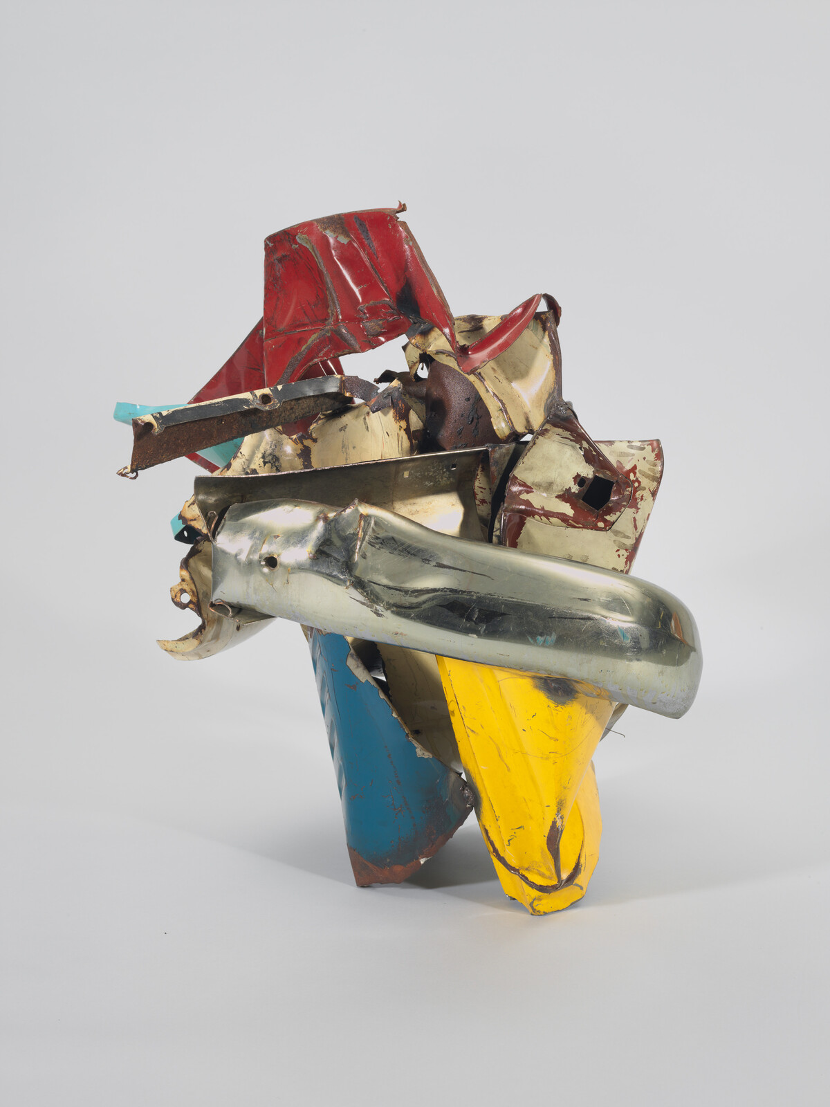 Crushed colorful metal sculpture made from twisted car panels and a chrome bumper.