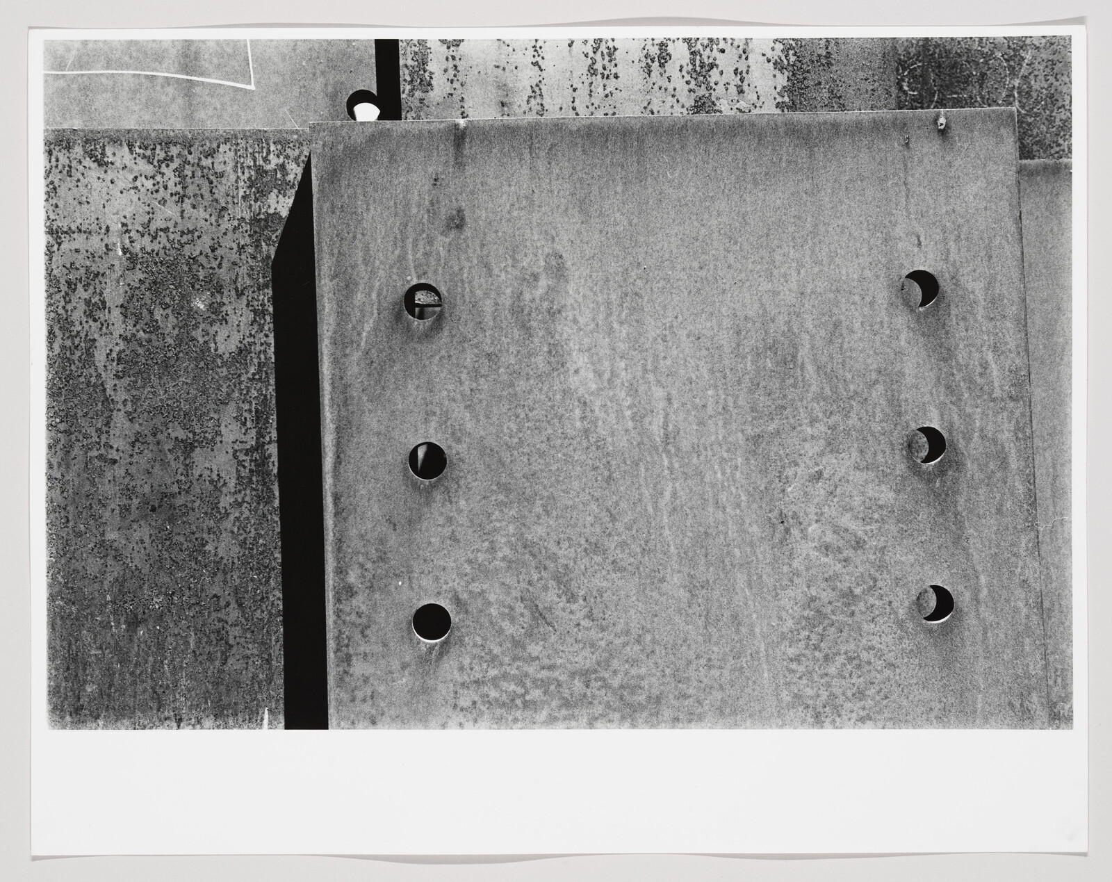 Large weathered metal plates with two vertical rows of circular holes and textured surfaces.