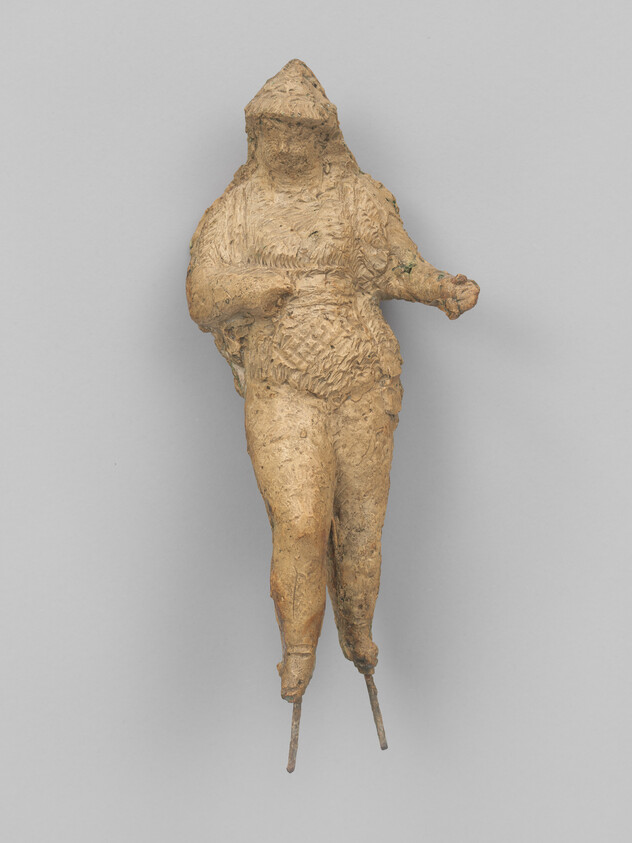 Small terracotta figurine of a hooded figure standing with thin support pins at the feet.