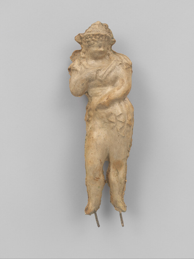 Small worn terracotta figurine of a standing person with one hand to chest and two metal pins.