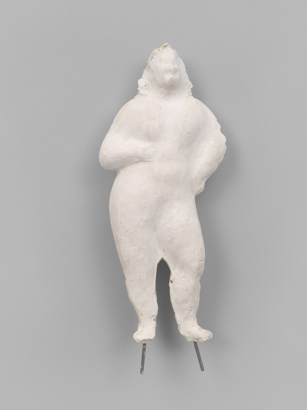 White plaster sculpture of a standing human figure with hands on hips and metal rod legs.