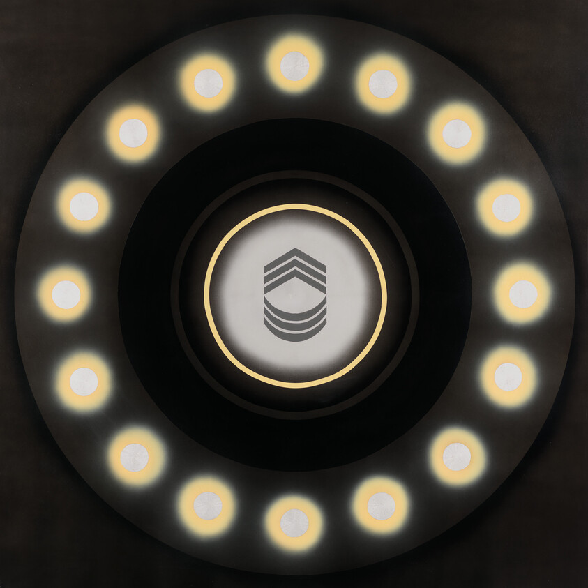 Circular ceiling light with two concentric rings of glowing bulbs and a shield-like emblem at center.