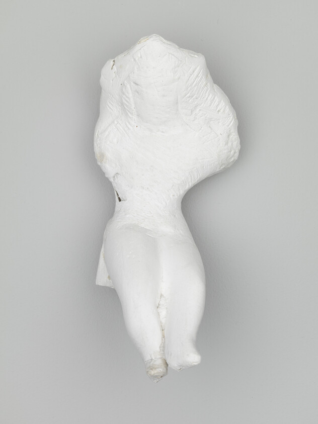 A white plaster torso with legs hanging against a gray background.