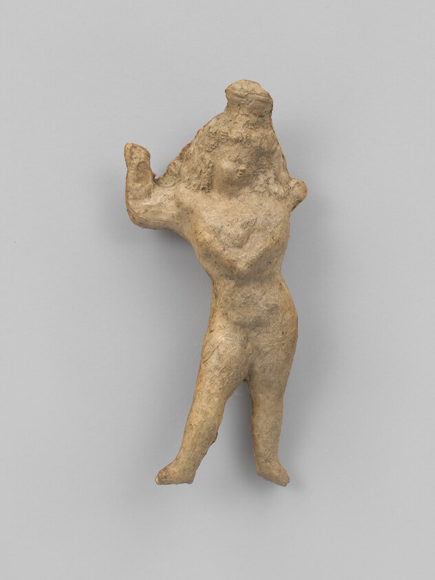 Small ancient clay figurine of a standing person with raised arms and a cone-shaped headdress.