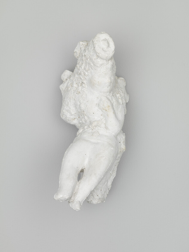 Small rough white plaster sculpture of a reclining torso with two legs extending downward.