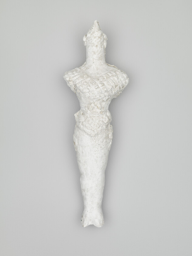 A tall white plaster sculpture of a stylized female figure with textured torso and narrow legs.