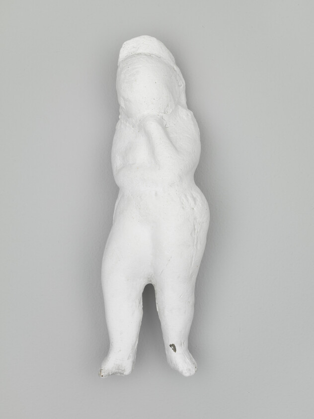 Small white plaster sculpture of a standing child with one hand raised to the face.