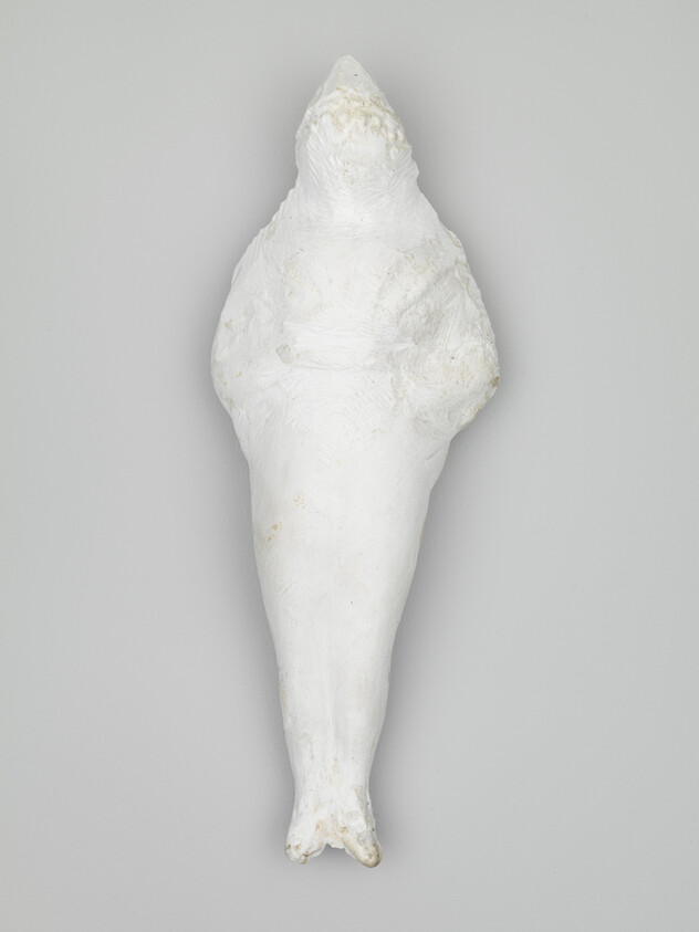 Long white sculptural object resembling a wrapped bird with a pointed top and tapered body.