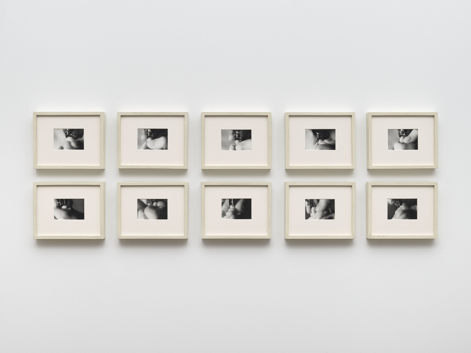 A grid of nine framed black and white photographs on a white wall.