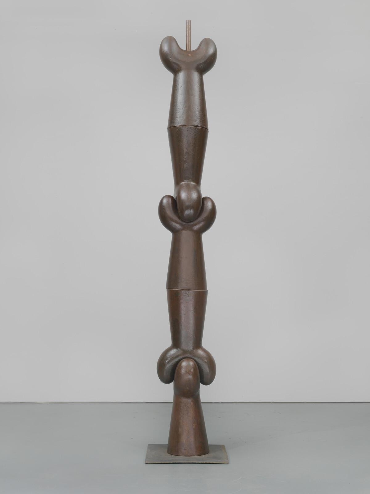 Five distinct smooth brown metal shapes fitted together ontop of each other to create a stacked horizontal form.