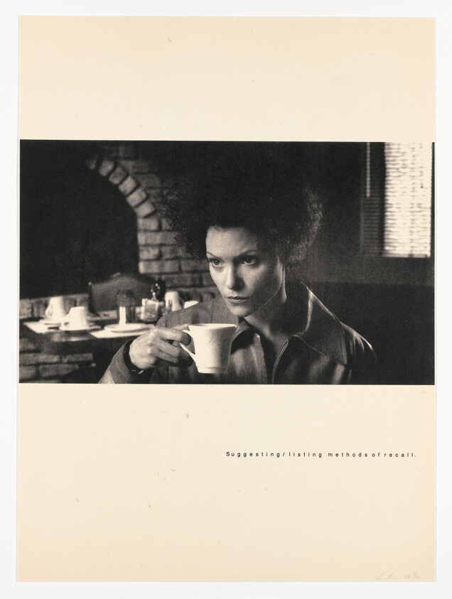 A woman sits in a café holding a cup and staring thoughtfully into the distance.