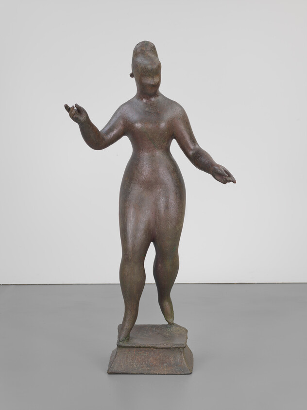 Bronze sculpture of a standing human figure with outstretched arms on a square base.