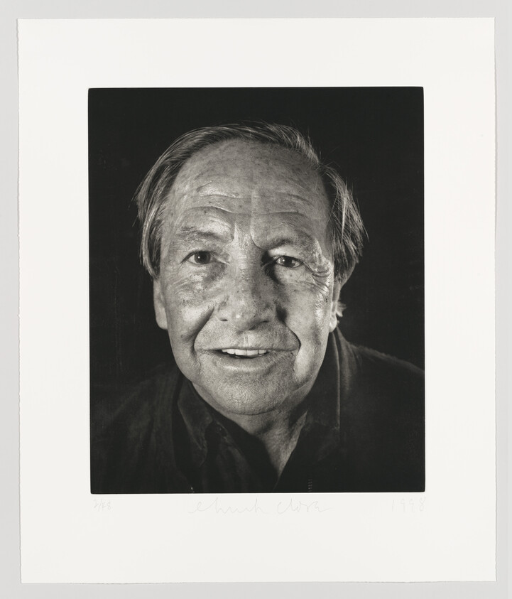 Black and white portrait of an elderly man with a warm expression, featuring prominent smile lines and a direct gaze. The photo includes a signature and date in the lower right corner.