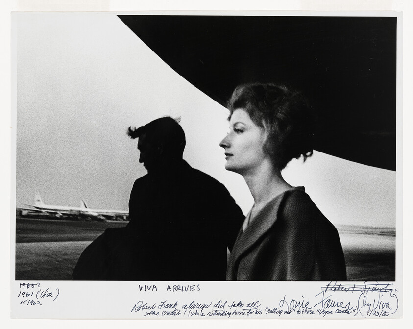 A woman in profile stands at an airport beside a silhouetted man under an airplane wing.