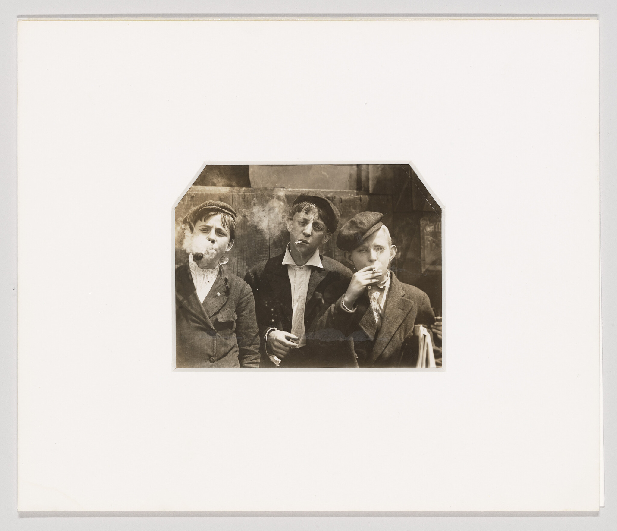 Vintage photo of three young men in suits, two blowing smoke rings and one eating, with a whimsical expression.