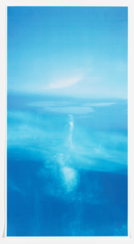 A lone figure rising through deep blue water toward a bright surface light.