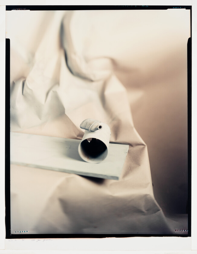 A small rolled paper tube resting on a wooden board against crumpled paper background.