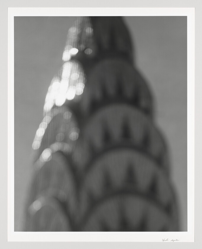 A fuzzy photo of the top of the Chrysler Building shimmering with sunlight.