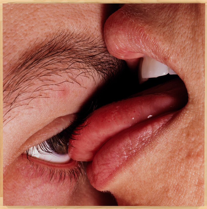Close-up of a person's eye and another's lips almost touching, highlighting facial details.