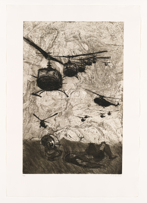 Several helicopters fly low overhead as two people lie on the ground below.