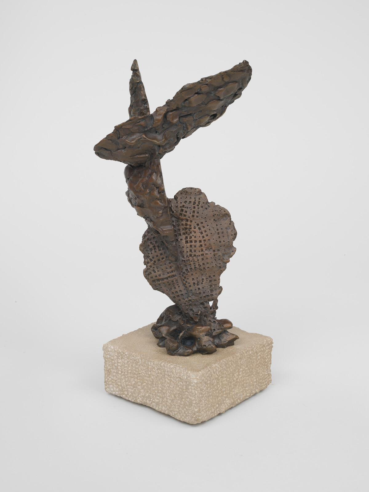 A bronze sculpture with an abstract design, featuring textured surfaces and irregular shapes, mounted on a square stone base.