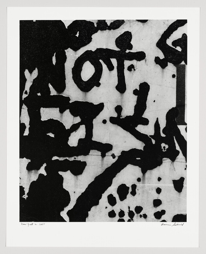 Large abstract black ink shapes and splatters on a white background resembling bold calligraphy.