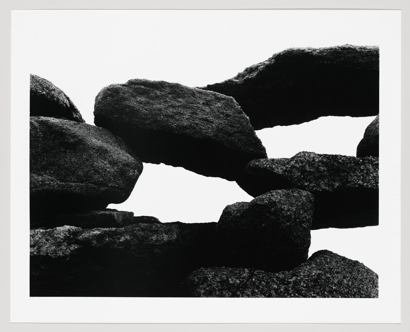 Large dark boulders stacked with gaps revealing bright sky between them.