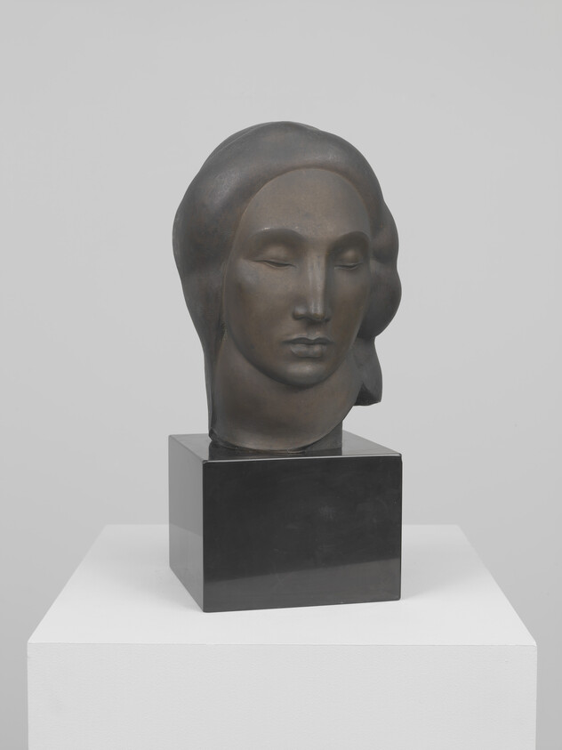 Bronze bust of a serene woman with closed eyes on a black pedestal.