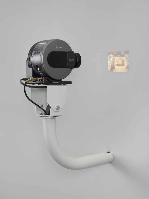 A Sony camcorder is mounted on a white wall bracket projecting a small color image.