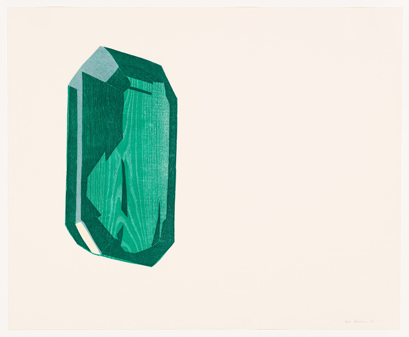 A large faceted green emerald crystal shown against a plain light background.