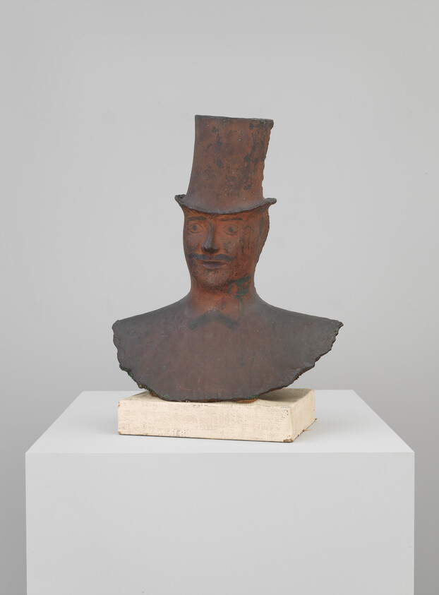 Rusty metal bust of a man wearing a tall top hat on a white pedestal.