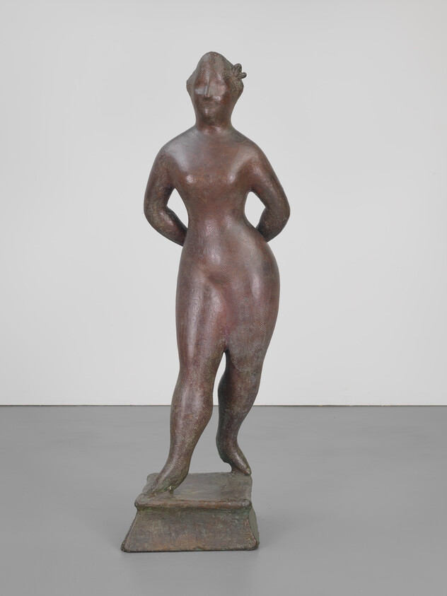 Bronze sculpture of a standing nude woman stepping forward with hands behind her back on a pedestal.
