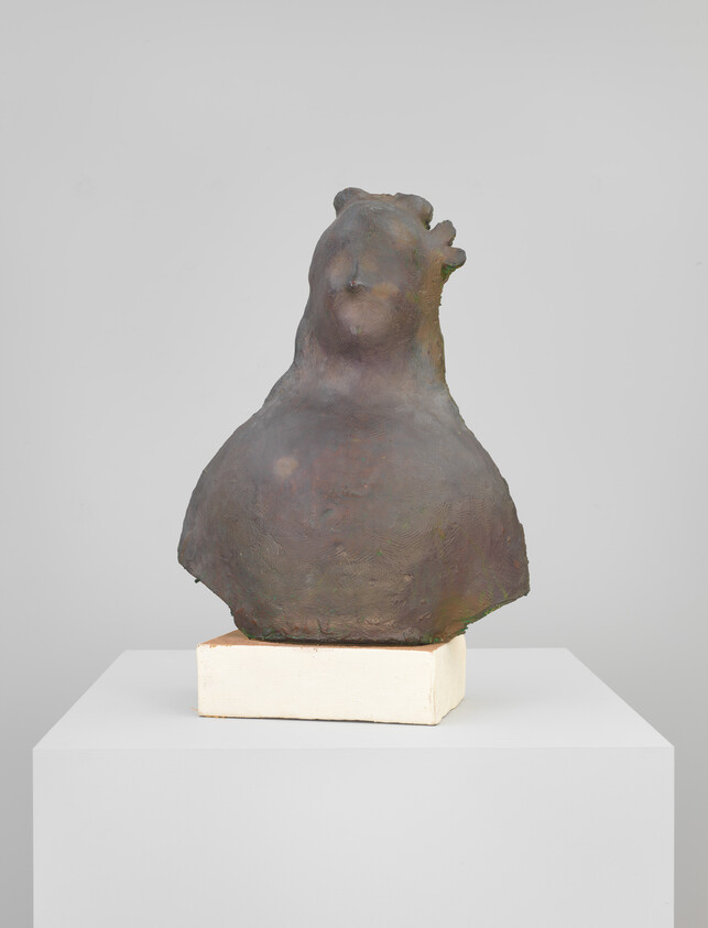 A dark, rounded abstract bust sculpture displayed on a white block pedestal.