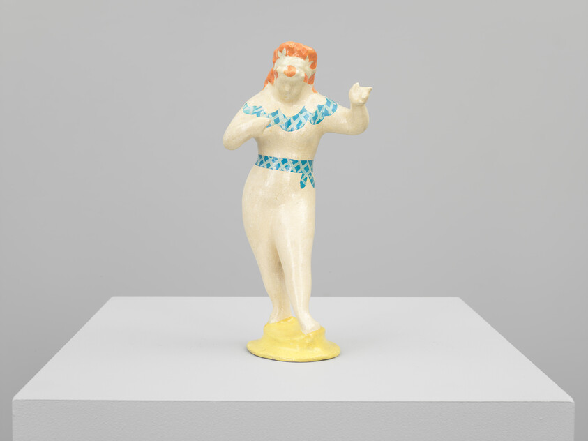 A small ceramic female figurine with red hair wearing blue patterned swimwear on a yellow base.