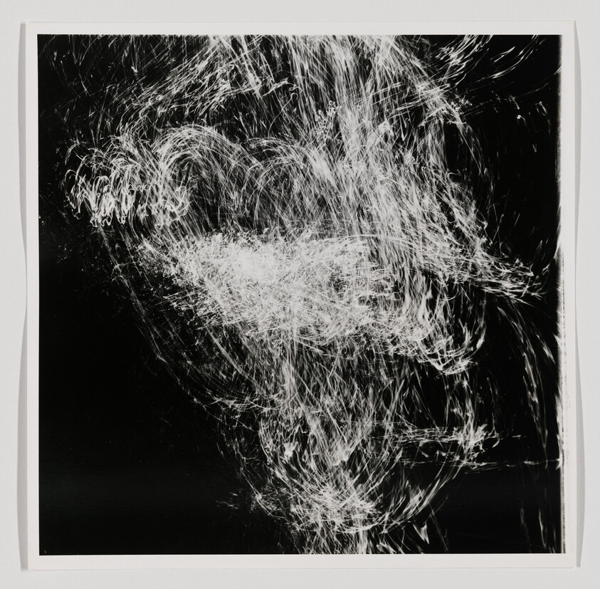 White light trails swirl and tangle against a black background, creating an abstract cloud-like pattern.