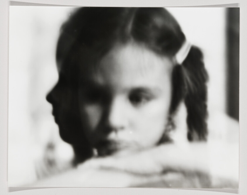 Young girl with pigtails rests her chin on folded arms with a faint profile overlay.