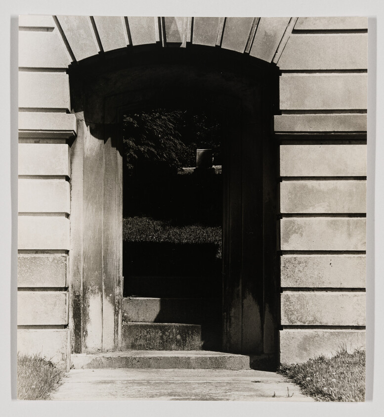 Stone archway leads to dark stepped passage with light grass visible beyond the opening.