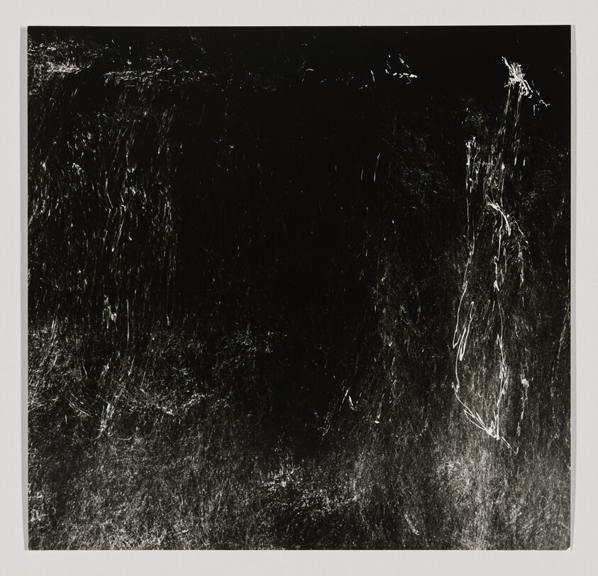 Dark square with white scratches and textured marks concentrated along right and bottom edges.