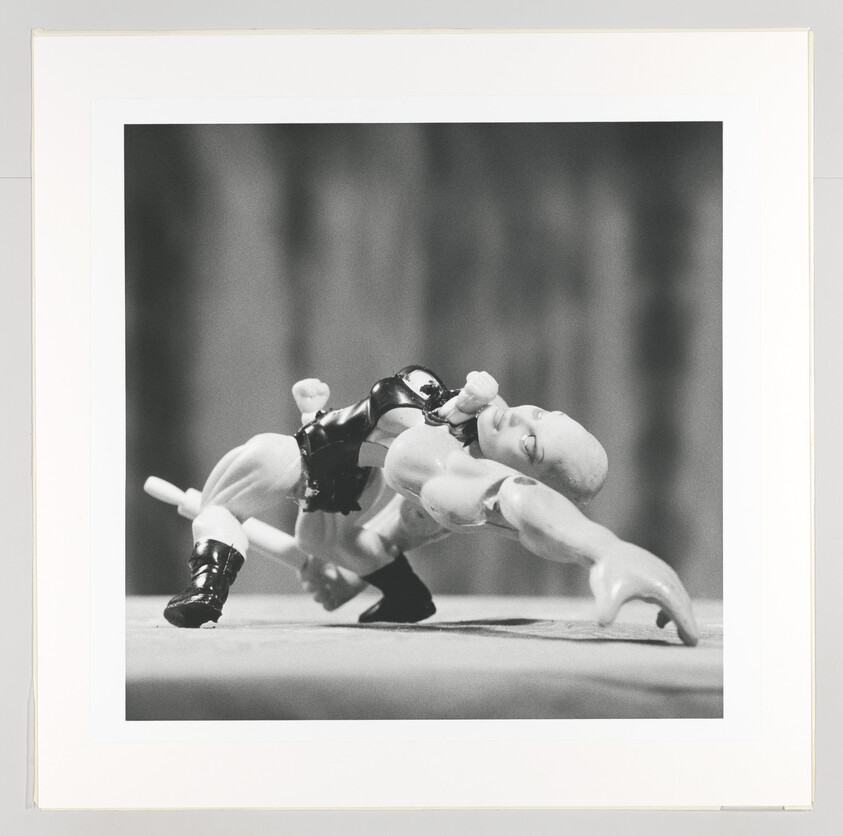 Two wrestling action figures grappling on a flat surface with one figure stretching backward.