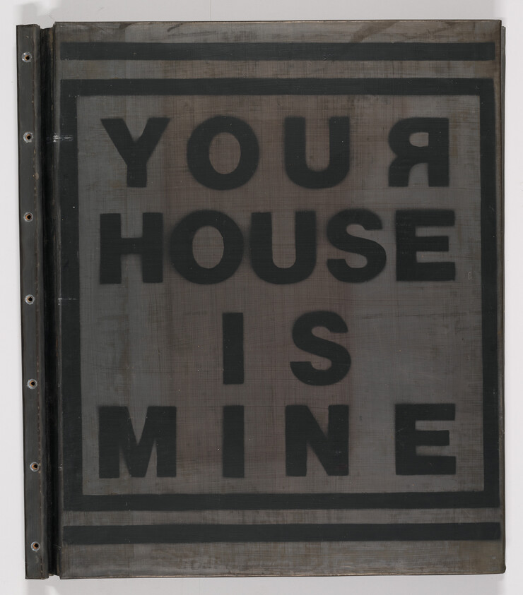Large printed sign reading "YOUR HOUSE IS MINE" in bold black letters within a bordered frame.