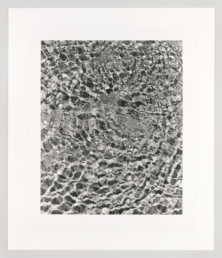 Black-and-white framed print showing rippling water patterns and light reflections.