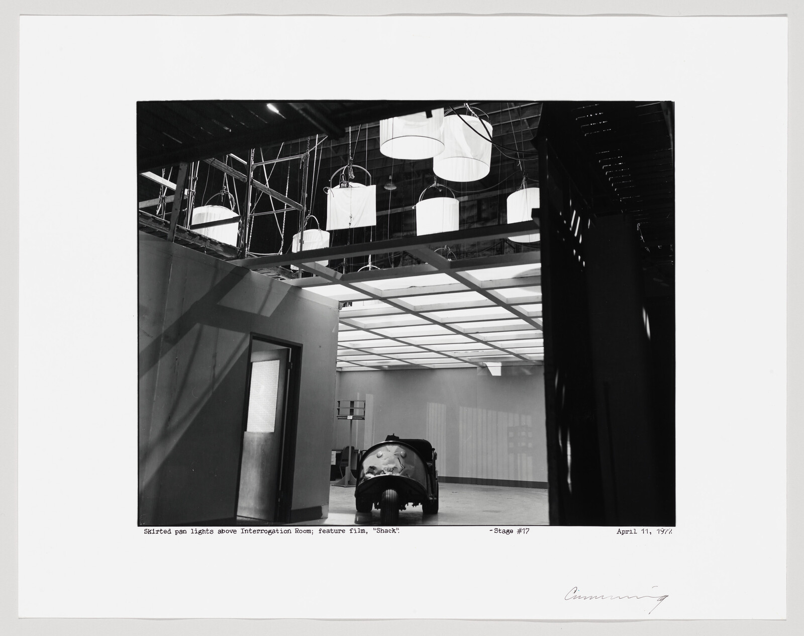 Studio set with suspended round lights and a small car in an empty interrogation room.