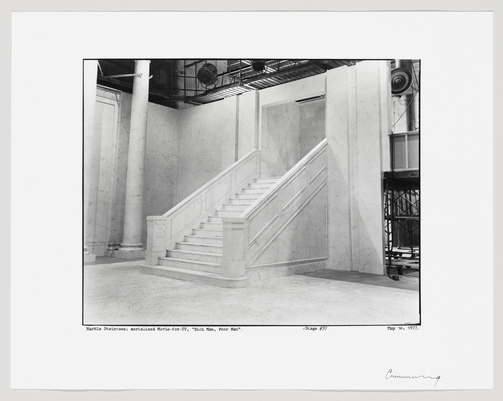 A grand marble staircase with balustrades on a studio stage set, surrounded by columns and rigging.
