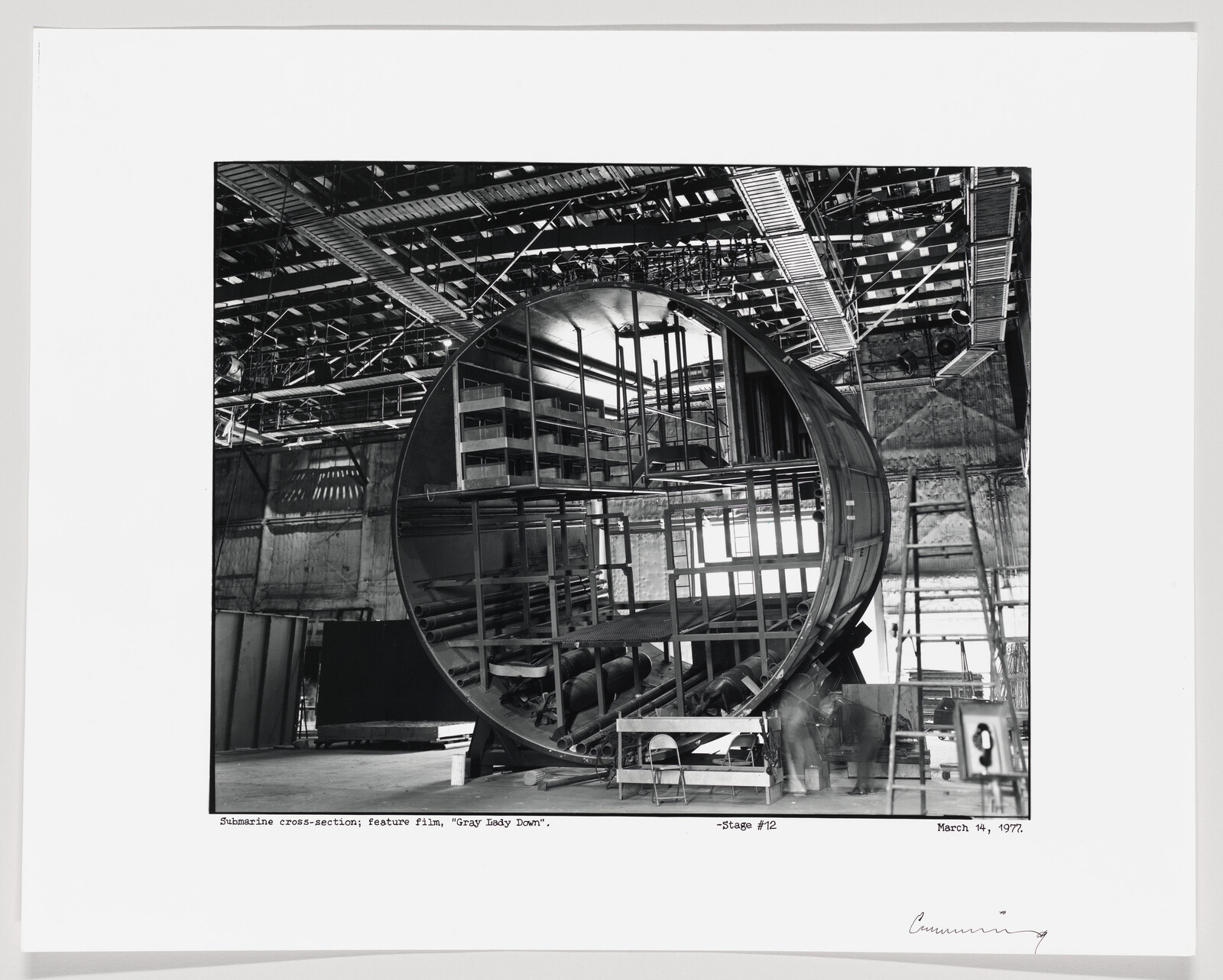 Large circular submarine cross-section set inside a studio with scaffolding and ladders.