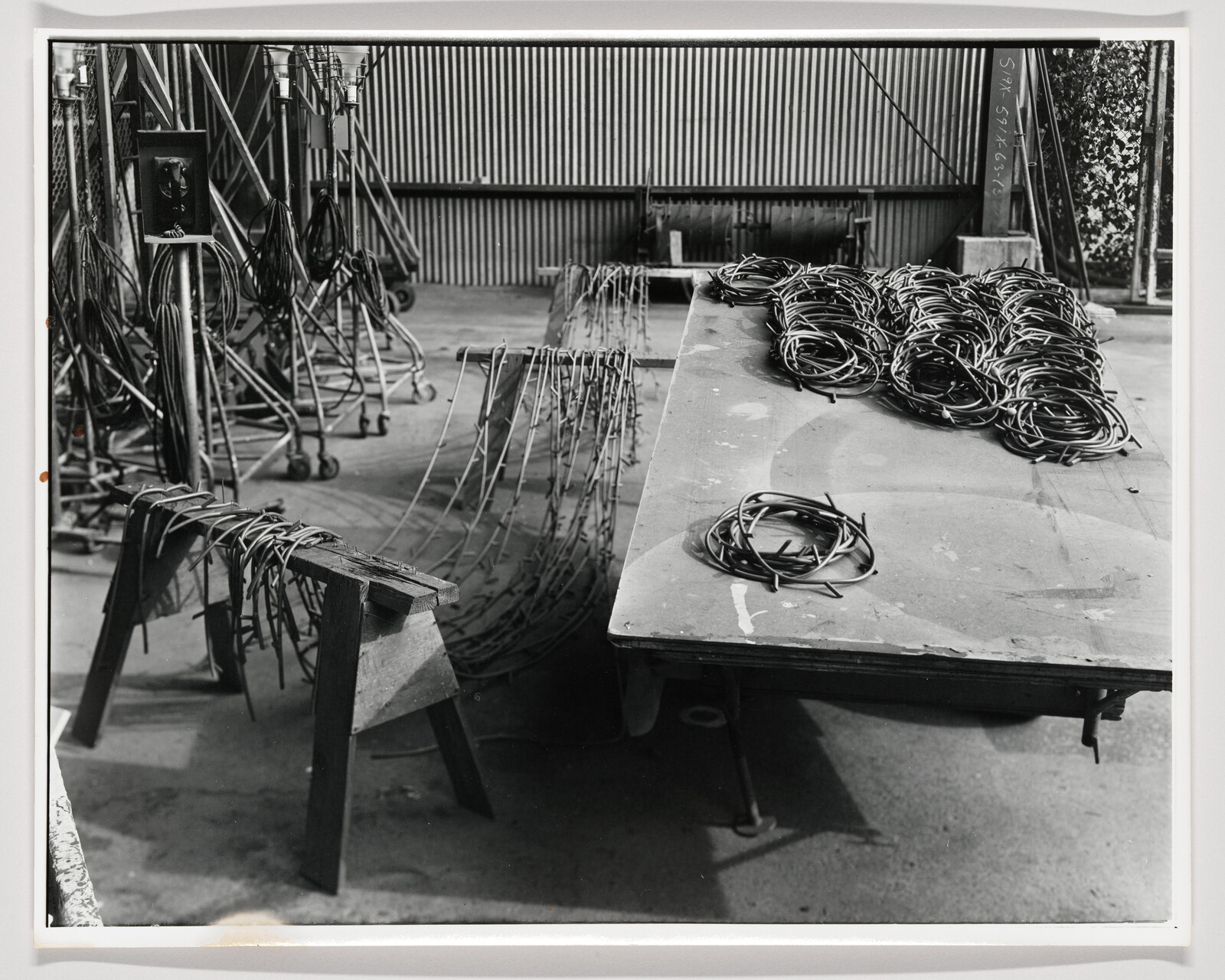 Coiled electrical cables organized on a large worktable with more wires draped over a nearby sawhorse.