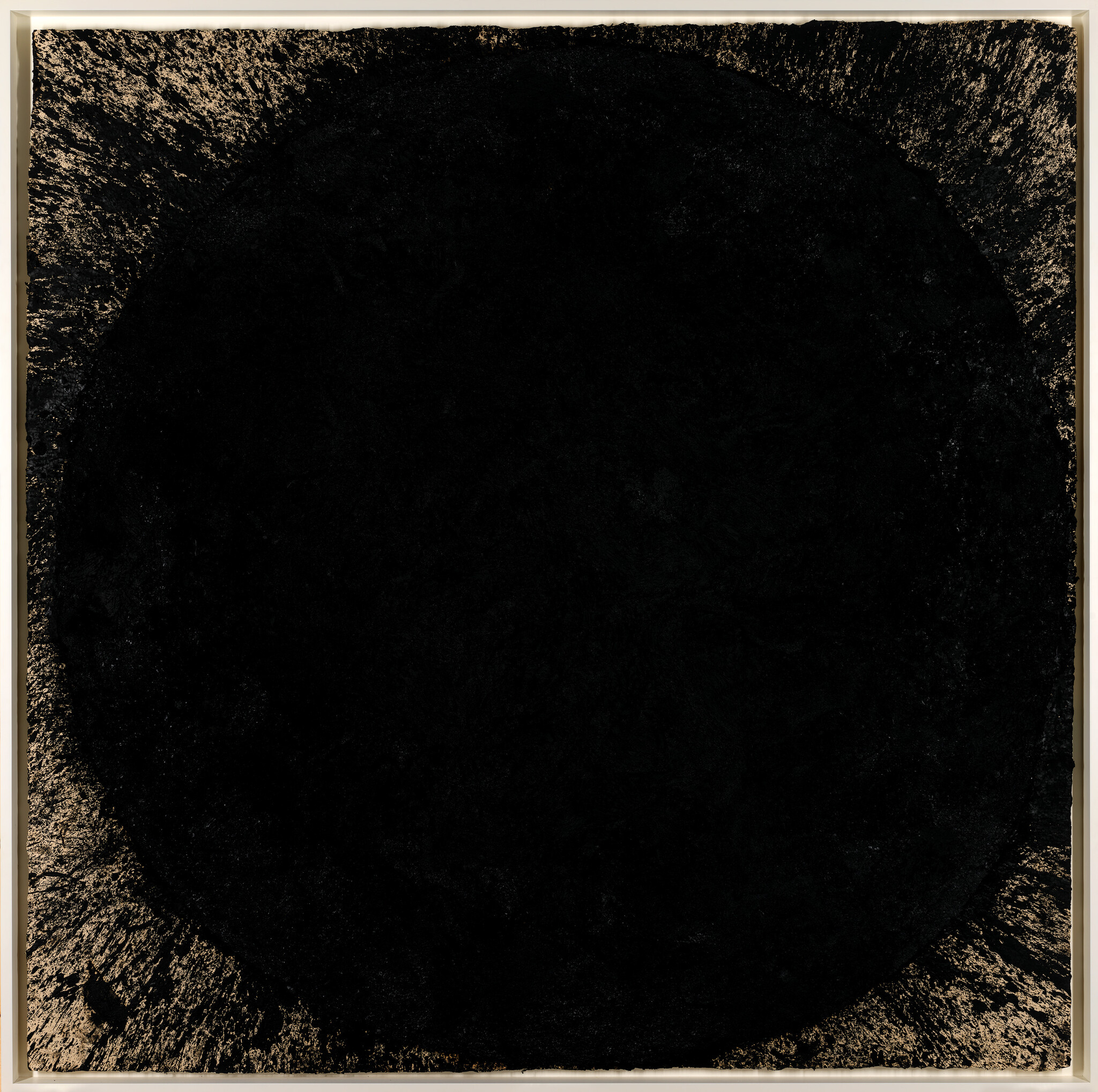 Large solid black circle with textured gold-fleck edges inside a thin beige frame.