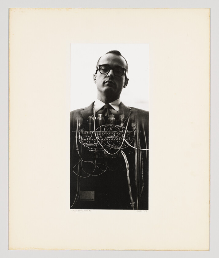 Man wearing glasses and a suit overlaid with tangled electronic wires and tubes.