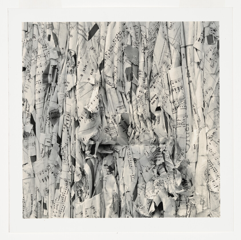 Stacks of crumpled and folded sheet music pages tightly packed together in a square frame.